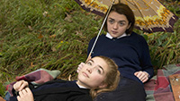 Image of two girls leaning on each other and looking up at the sky